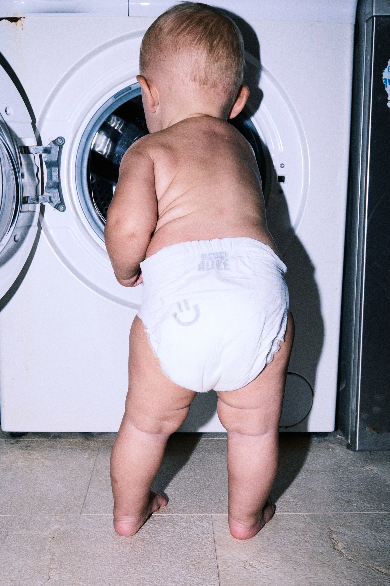Toddler in a Rebelalike diaper looking into a washing machine