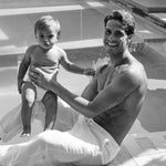 Dad holding a baby in a Rebelalike diaper by the pool, black and white