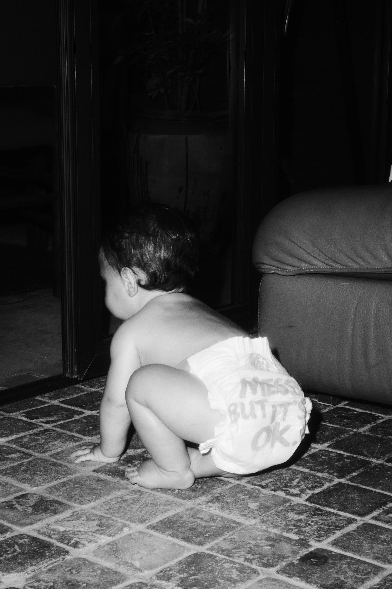 Baby crawling in a Rebelalike diaper with Messy But It's OK print, black and white