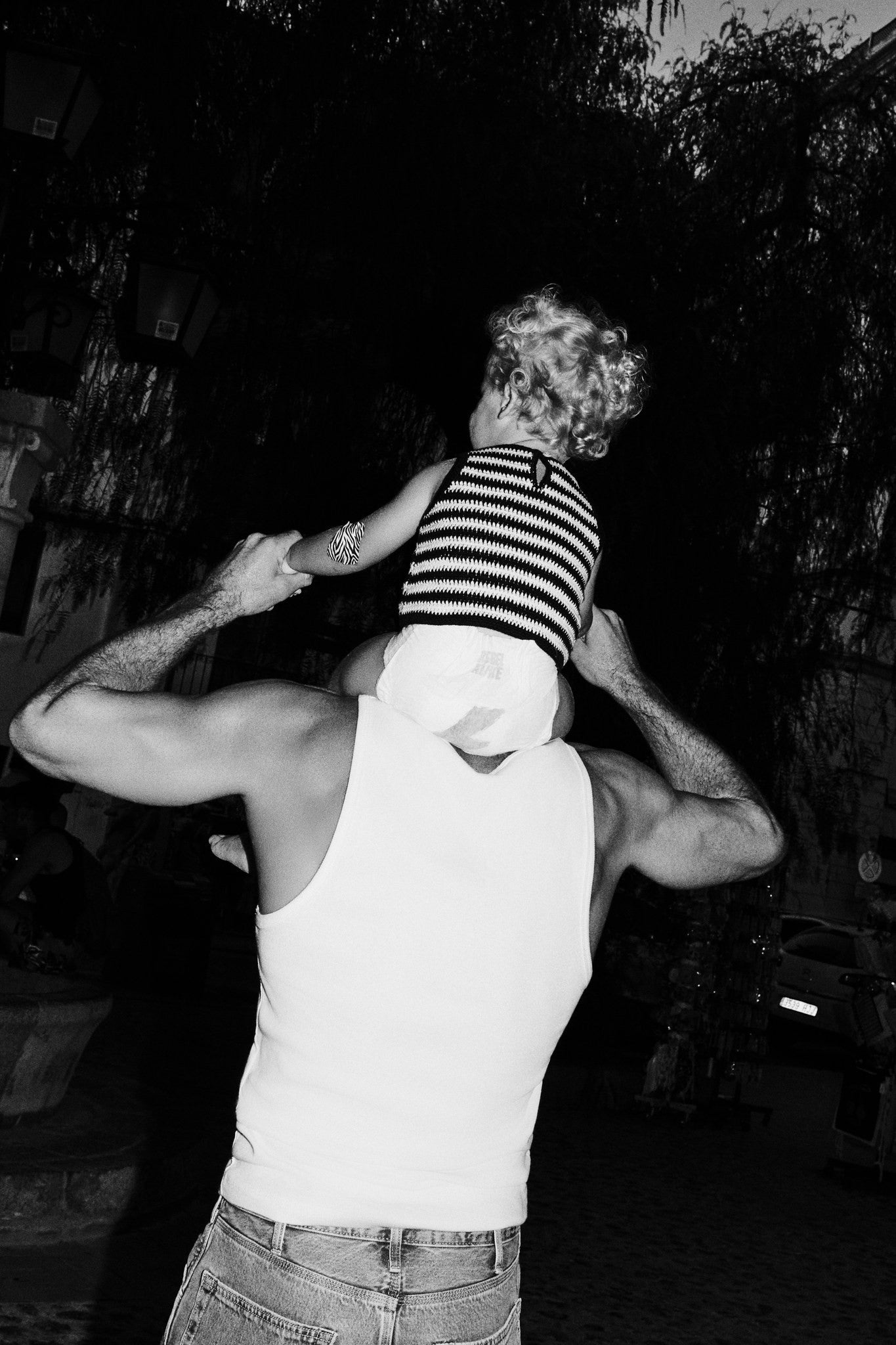 Dad carrying a toddler in a Rebelalike diaper on his shoulders, black and white