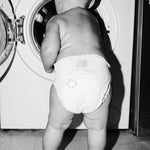 Toddler in a Rebelalike diaper looking into a washing machine, black and white