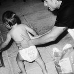 Toddler in a Rebelalike diaper walking past a pack of Rebelalike diapers, black and white